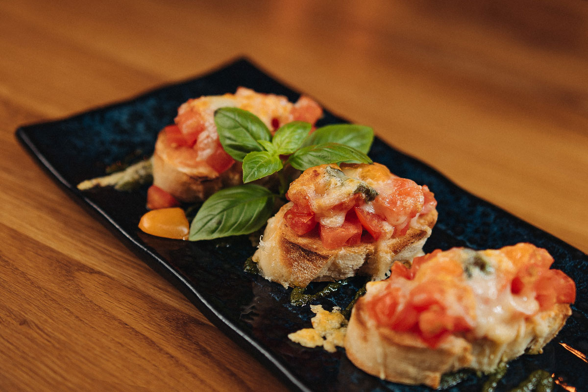 Bruschetta classic cheese mit Tomatenwürfeln, Knoblauch und frisch gehobeltem Parmegiano überbacken